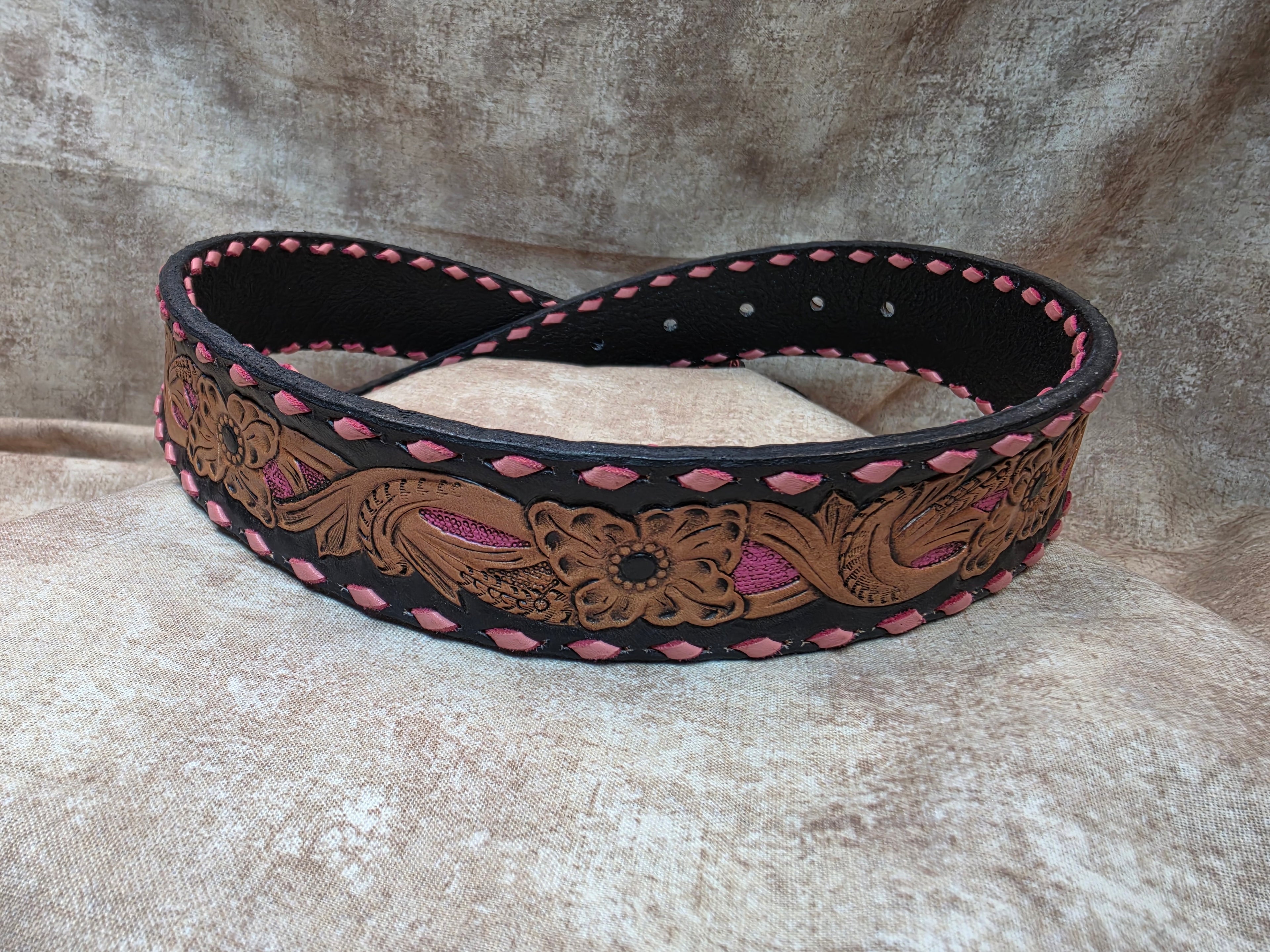 Hand tooled, black and pink buck stitched western belt. Size 28".