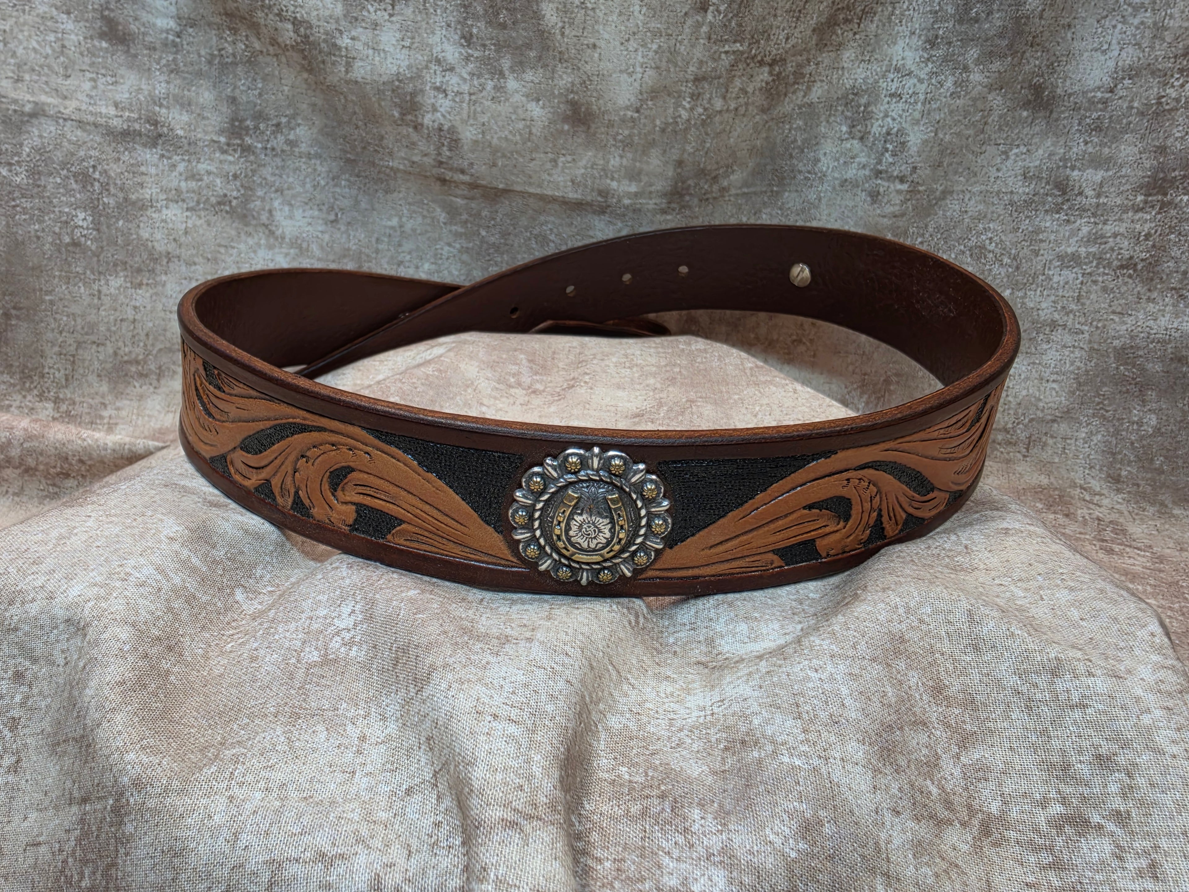 Hand tooled, mahogany colored, western belt with silver and gold colored horseshoe conchos. Size 32".