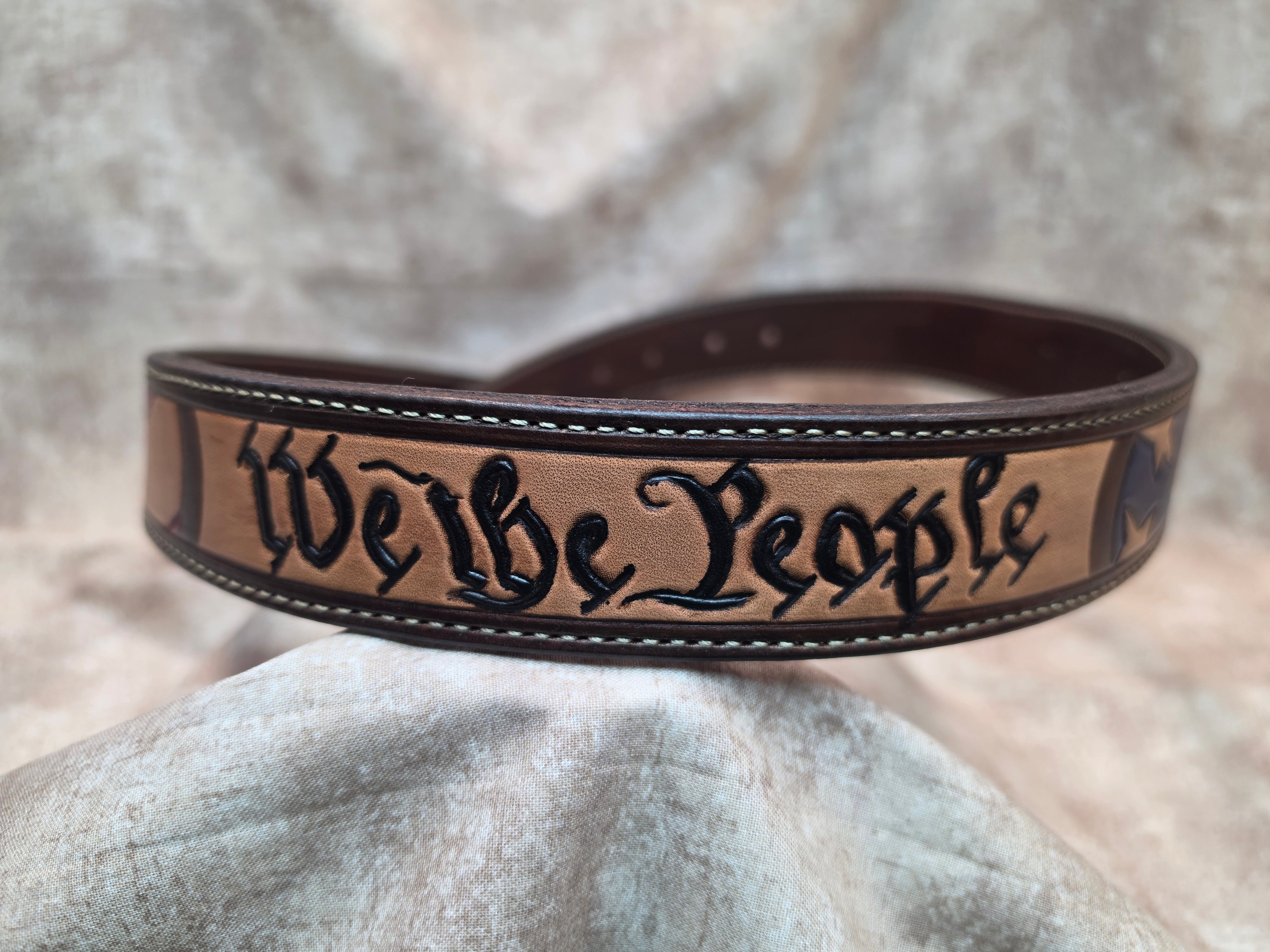 Hand tooled, western belt with 'We the People' theme, including flag, lined back, sewn edges, tooled keeper. Size 37".