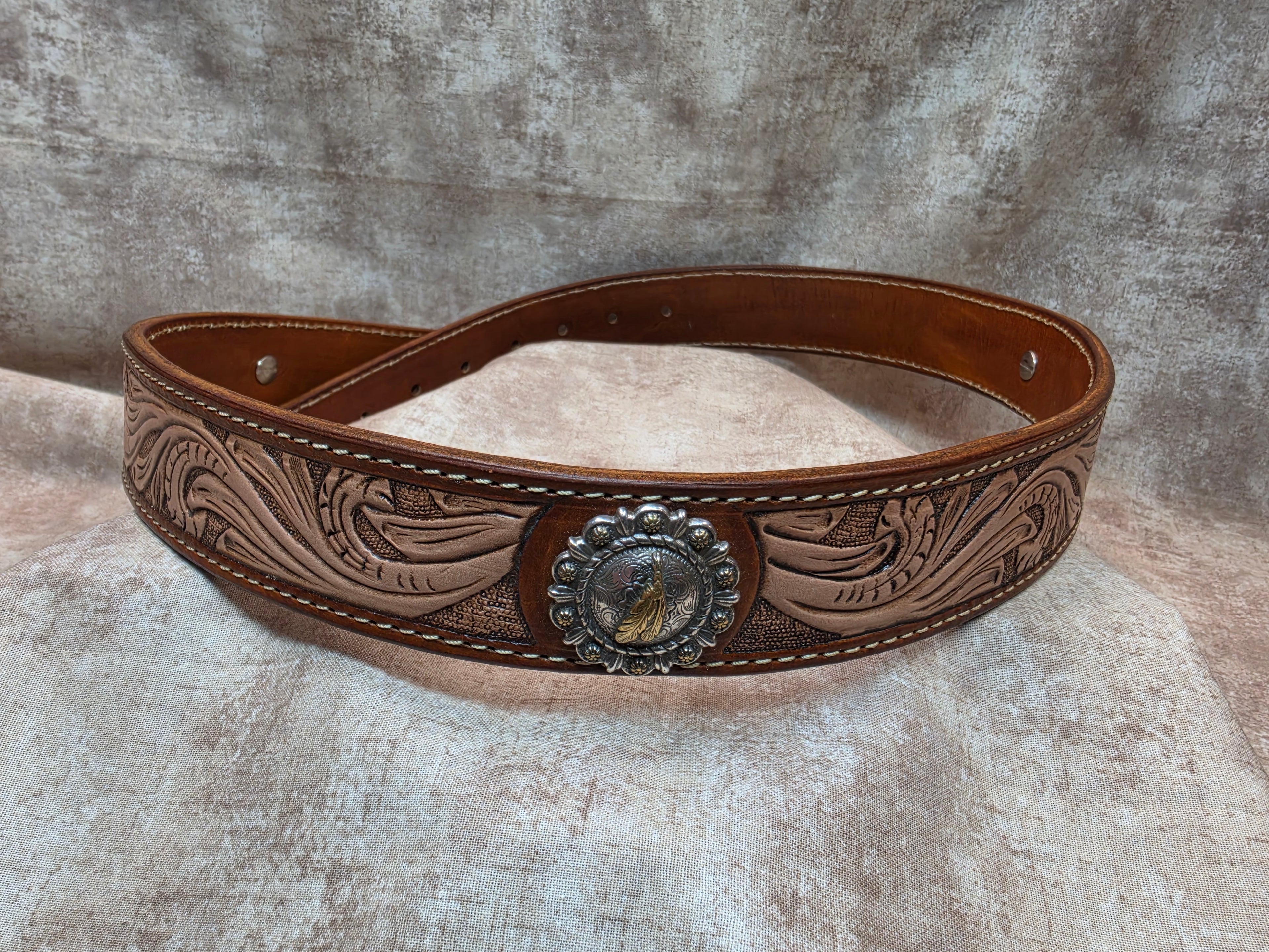 Hand tooled, golden brown, western belt with silver and gold colored feather conchos. Size 38".