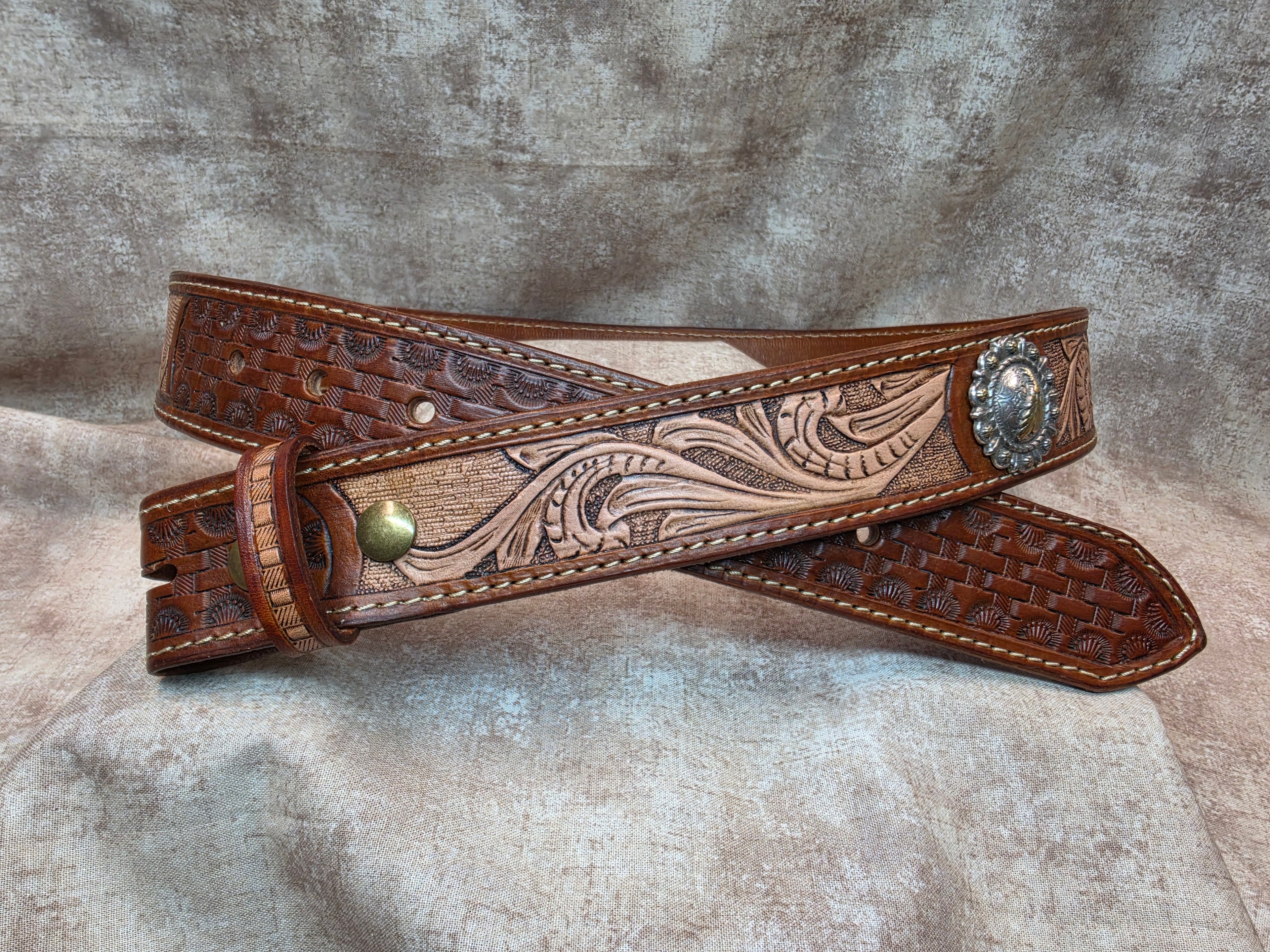 Hand tooled, golden brown, western belt with silver and gold colored feather conchos. Size 38".