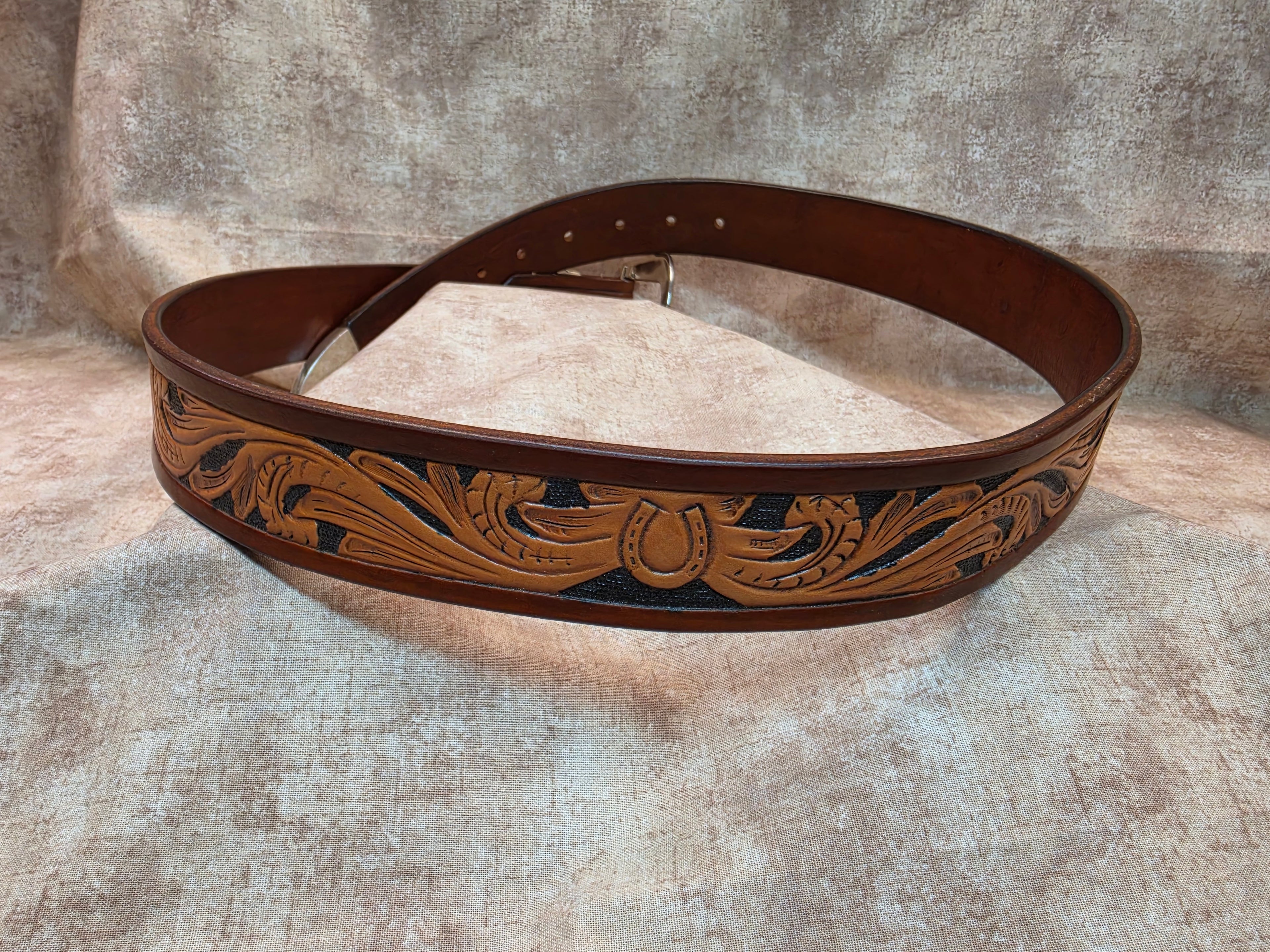 Complete hand tooled, western belt with silver and gold colored buckle, keeper and tip. Size 38".