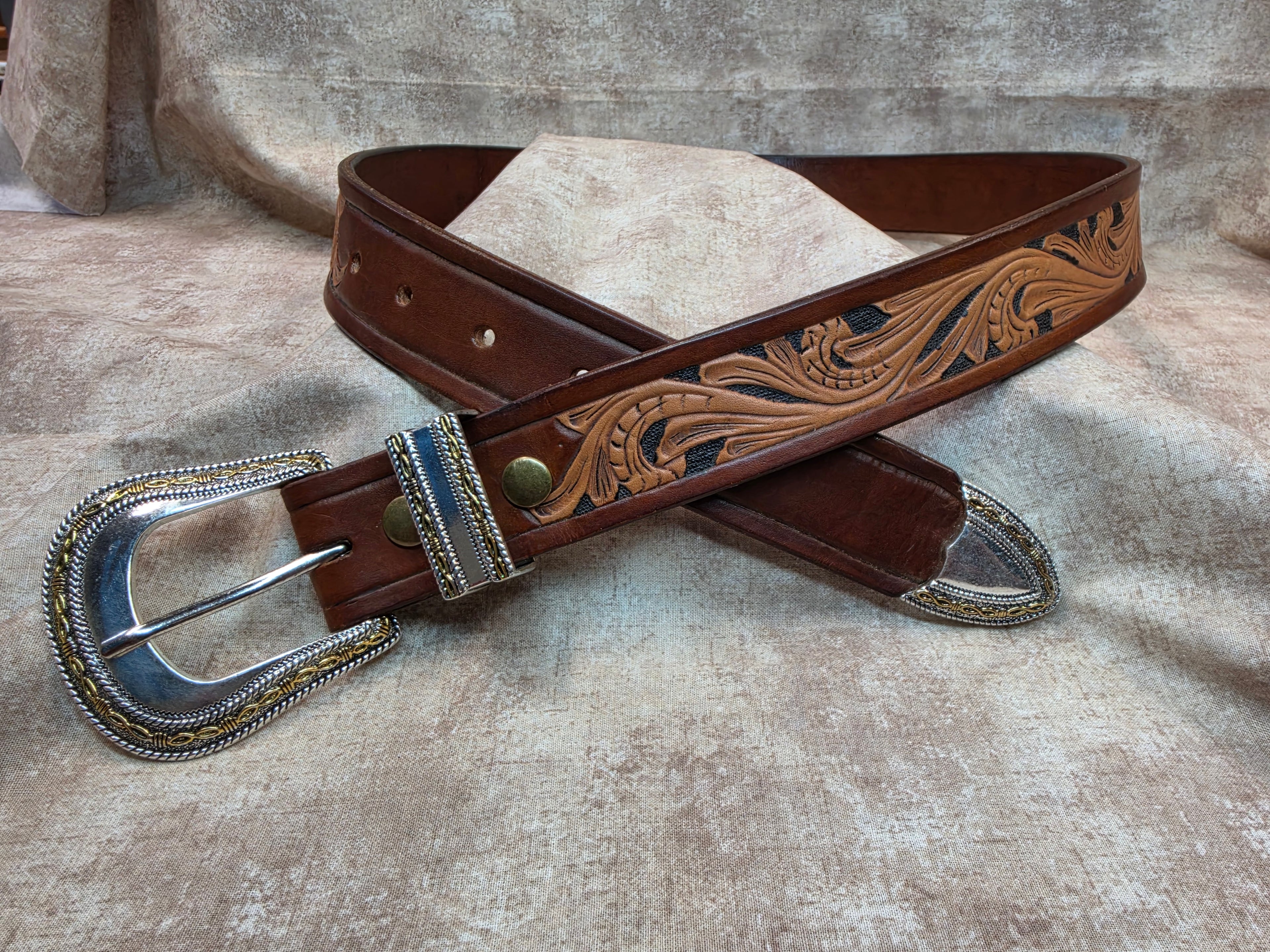 Complete hand tooled, western belt with silver and gold colored buckle, keeper and tip. Size 38".