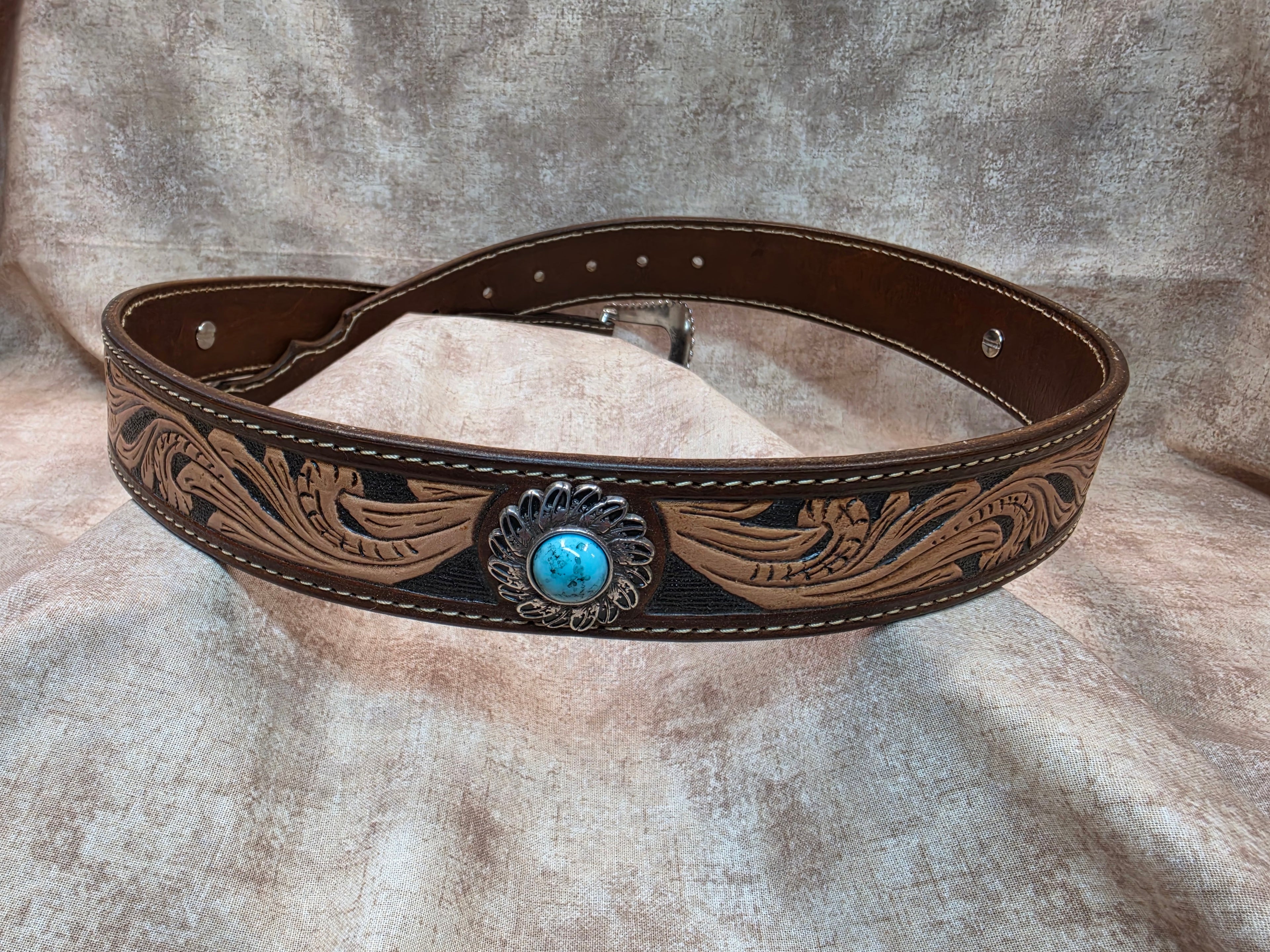 Complete hand tooled, western belt with silver and turquoise colored buckle, novelty tip, lined back, sewn edges, tooled keeper. Size 36".